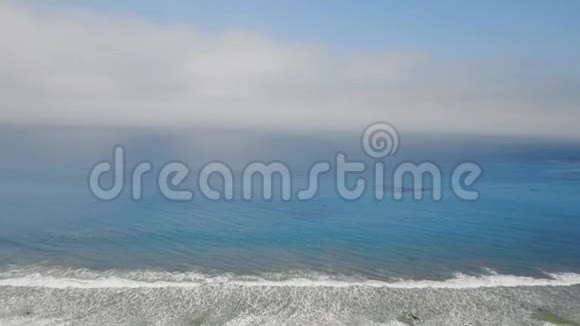 空中拍摄的雾蒙蒙的地平线蓝色的海洋和海滩上的房子视频的预览图