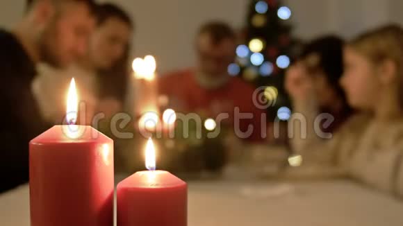 男人在桌子上点蜡烛他的大家庭一起吃午饭背景圣诞树视频的预览图