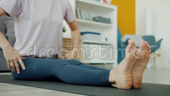 在家做瑜伽的漂亮女士的特写镜头在室内屈膝于垫子上视频的预览图