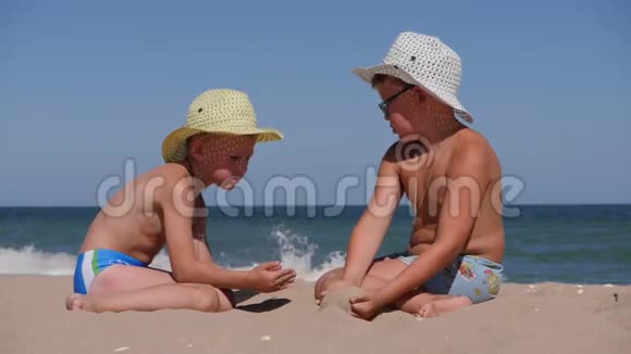 和孩子们一起在海上休息沙子从手掌心倒入孩子手心两个男孩戴帽子视频的预览图