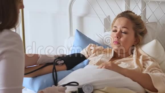 一位穿着白色外套的医生在床上休息时在家咨询一位妇女私人医生保健概念视频的预览图