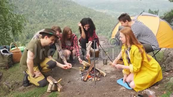 年轻的徒步旅行者花时间在营地准备食物周末和朋友在一起视频的预览图