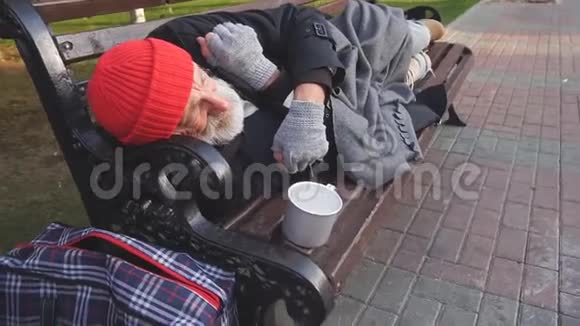 寒冷的天气可怜的流浪汉躺在长凳上视频的预览图