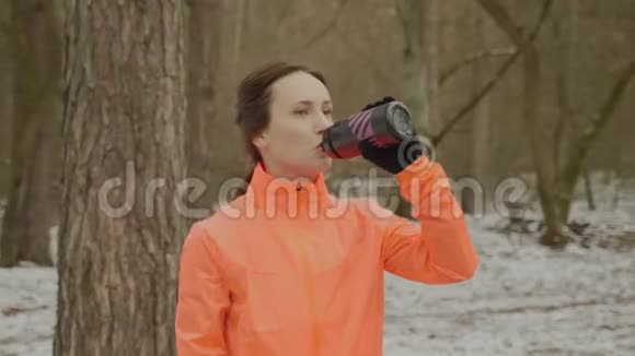 疲惫出汗的女人跑步后喝水训练后女性从瓶子里喝等渗酒年轻可爱的爱跑的女孩视频的预览图