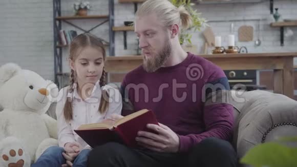年轻的白种人坐着看书和十几岁的女孩说话布鲁内特漂亮的女儿摇头是的家庭视频的预览图