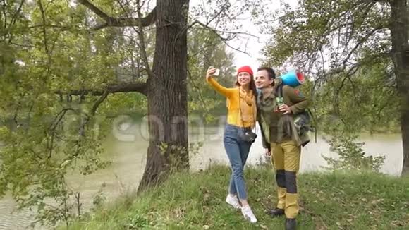 穿着旅游服装的漂亮夫妇在秋天的森林里拍照视频的预览图