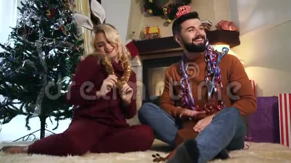 欢快的夫妻坐在装饰好的圣诞树前跳舞快乐的白人男女视频的预览图
