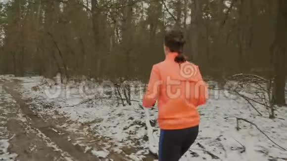 女人在公园里跑步女性正在训练淡季穿着橙色夹克和蓝色紧身衣的女孩在户外慢跑专业运动员预科视频的预览图