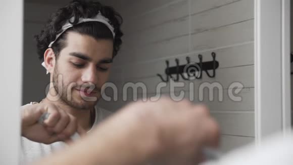 大胡子男在浴室的镜子前刷牙视频的预览图