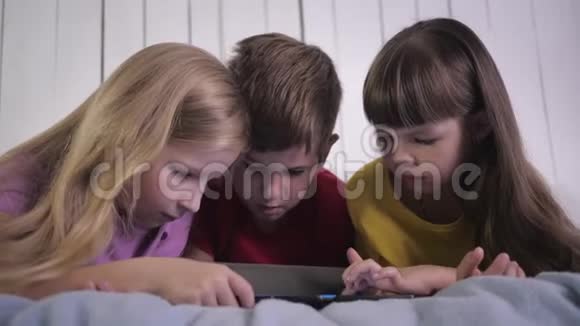 现代孩子小男孩和女孩使用平板电脑在家里躺在床上放松时交流视频的预览图