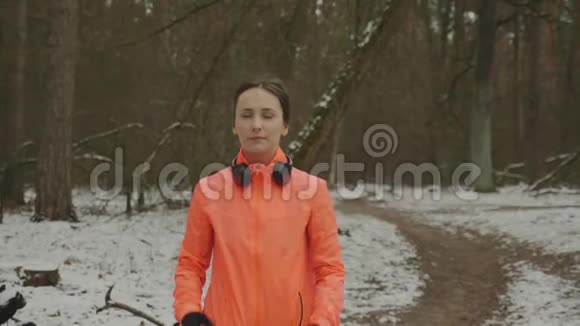 女性戴上耳机开始在冬季公园慢跑自信的年轻女子每天跑步和做户外运动视频的预览图