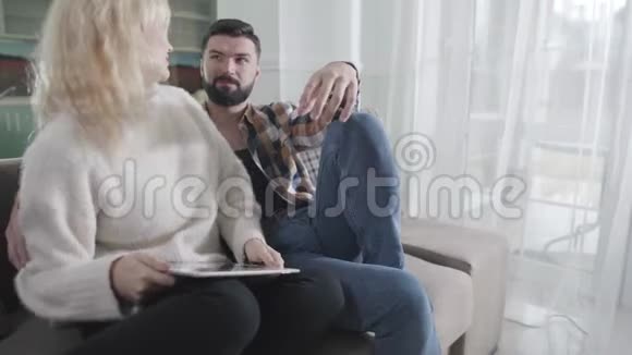 活跃的白种人夫妻讨论情绪在线问题积极的男人和女人在室内的沙发上休息视频的预览图