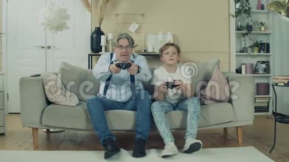 一个男孩和他爷爷正坐在沙发上玩电子游戏视频的预览图