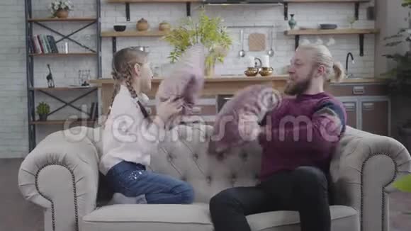 开朗的白种人男人和十几岁的女孩辫子和枕头打架爸爸和女儿在家玩得开心视频的预览图