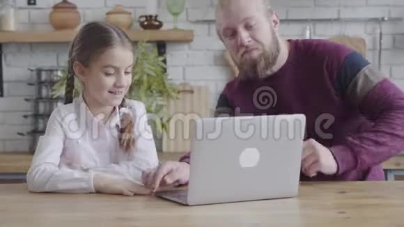 积极的白种人男人和可爱的女孩坐在笔记本电脑和交谈父女利用社交媒体视频的预览图