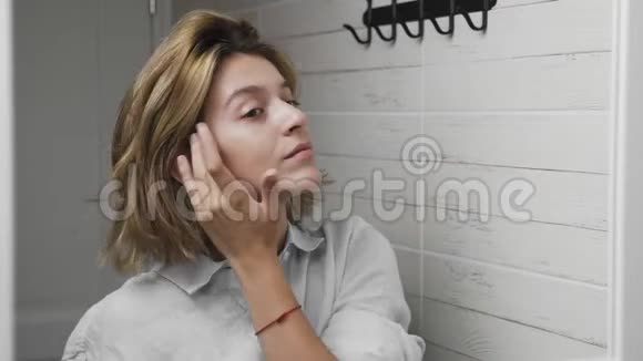 年轻的女人摸着她的脸和头发女人照镜子视频的预览图