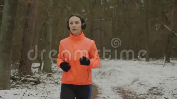 戴着耳机慢跑的女人年轻健康专注的女人在冬季公园里激烈地跑步每天做健身运动的女孩视频的预览图