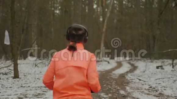 戴着耳机的女人在公园里完成了锻炼后侧跟随运动女运动员在冬季公园跑步吉吉视频的预览图