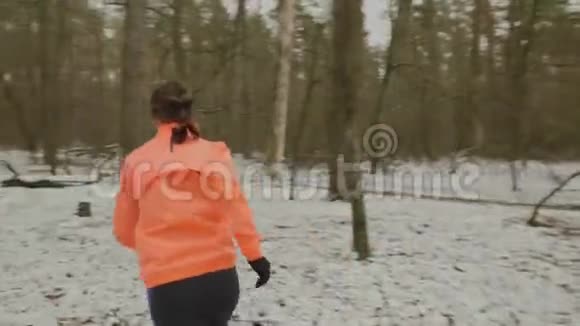 女人在森林里奔跑年轻自信的女性在冬季森林的树丛中慢跑运动服装女人逃跑了视频的预览图