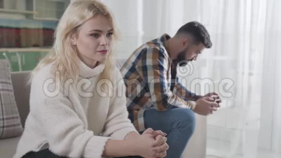 年轻沮丧的白种人女孩看着一边坐在后台的长胡子男人有困难的夫妻视频的预览图