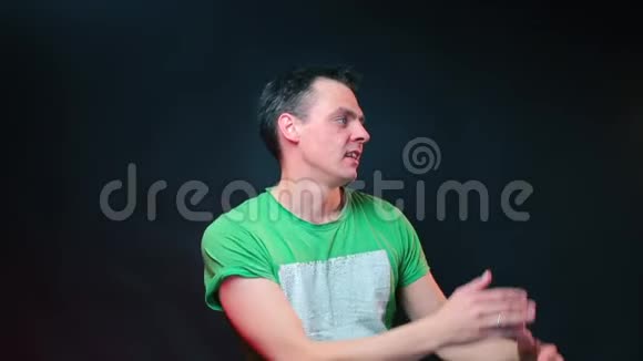 一个穿绿色T恤的男人在绿色背景上做鬼脸视频的预览图