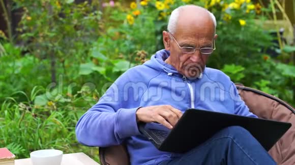 疲倦的老人拿起眼镜在笔记本上工作视频的预览图
