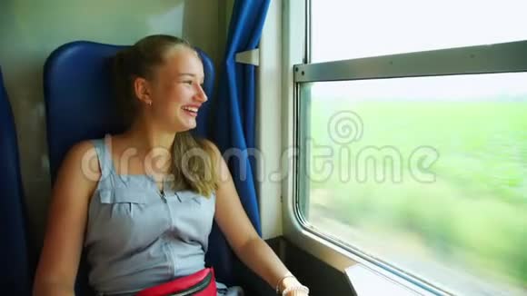女孩笑着指着火车开着的窗外的风景视频的预览图