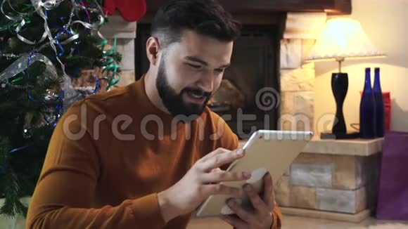 用平板电脑上网挑选圣诞礼物的白人年轻人的特写微笑的人在过新年视频的预览图