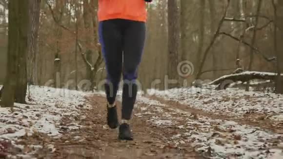 穿着紧身衣和在户外跑步的运动鞋的腿女腿在公园里跑冬天女人在森林里慢跑视频的预览图