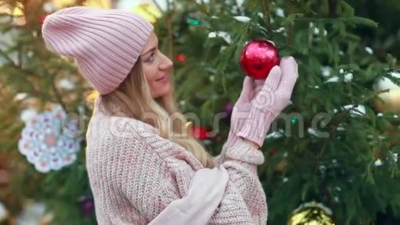 一个穿粉色毛衣的女孩在街上拿着一个圣诞树玩具视频的预览图