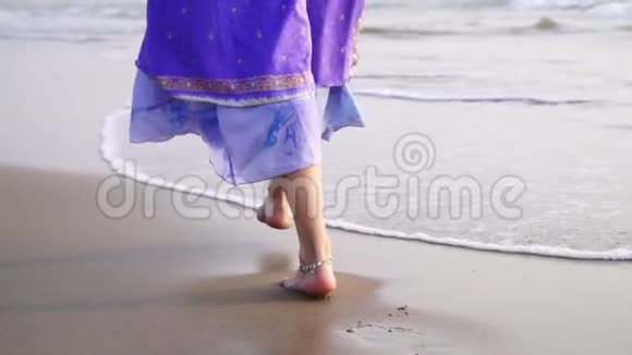 一个穿着东方服装的女人正沿着海滨散步双腿合拢视频的预览图
