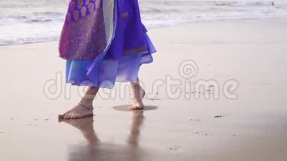 一个穿着印度服装的女人沿着海滩散步双腿合拢视频的预览图