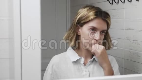 带牙刷的年轻漂亮女孩刷牙女人刷牙和看镜子的特写镜头视频的预览图