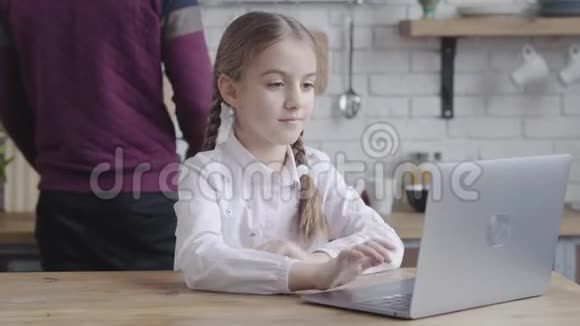 一位美丽的白种人少女在笔记本电脑键盘上打字而一位面目全非的男子在电脑旁做饭视频的预览图