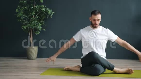 男瑜伽老师在明亮的垫子上展示现代工作室中的牛脸视频的预览图
