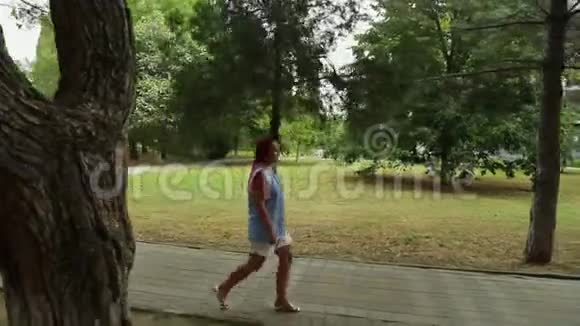 一个女人沿着公园里的石头走道走视频的预览图