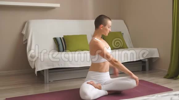 漂亮的女性坐在健身垫上摆出蝴蝶的姿势她伸展四肢伸腿视频的预览图