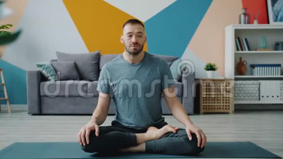 健康男人伸展脖子在家里做瑜伽垫上的运动照顾身体视频的预览图