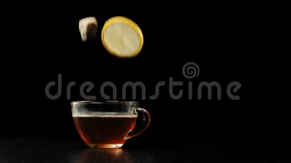茶道红糖和黄柠檬掉进一个透明的杯子里里面有水果红茶溅在黑桌上视频的预览图