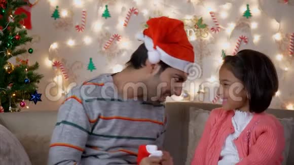 印度男人父亲给女儿戴上红色圣诞帽视频的预览图