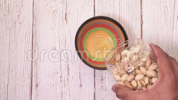 木桌上一个罐子里倒入开心果坚果的俯视图视频的预览图