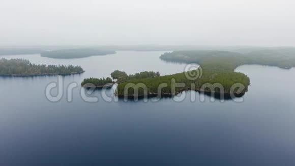 无人机在雾蒙蒙的地平线上靠近森林茂密的小岛屿加拿大安大略省威拉德湖视频的预览图