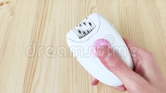 白色扩张器女性的手打开电动小工具来去除头发特写木制背景视频的预览图