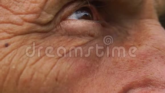 老人棕色的眼睛看着天空慢镜头近景视频的预览图
