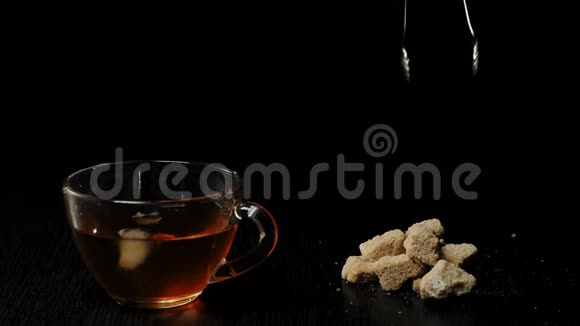 茶道手拿红糖放在透明的杯子里黑茶放在黑桌上背景黑视频的预览图