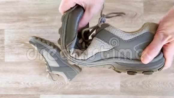 白手捏灰色运动鞋测试运动鞋橡胶鞋底的柔韧性以适应健身特写木制背景视频的预览图