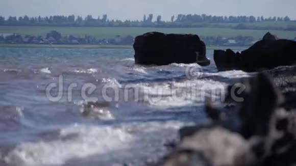 湖面上的波浪正在冲洗大石头视频的预览图
