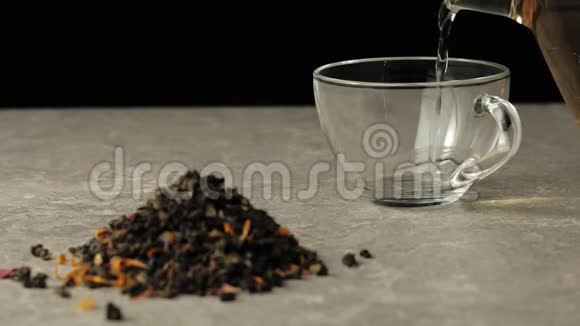 茶道绿茶被倒入一个透明的杯子里放在靠近绿茶堆的黑色背景的桌子上视频的预览图