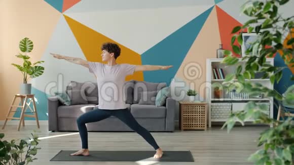 漂亮的年轻女子独自在现代公寓做瑜伽视频的预览图