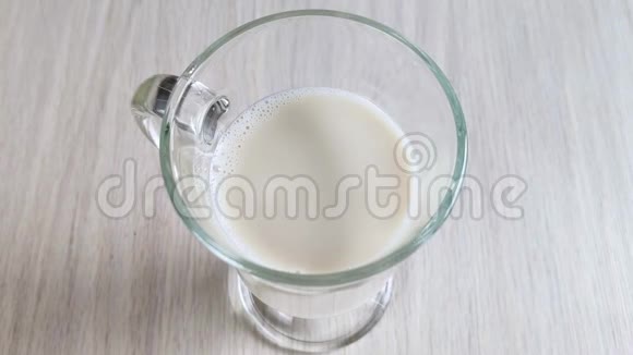 用带手柄的透明杯中的燕麦牛奶纯素替代奶牛乳制品不透明的奶油饮料倒入玻璃关闭视频的预览图